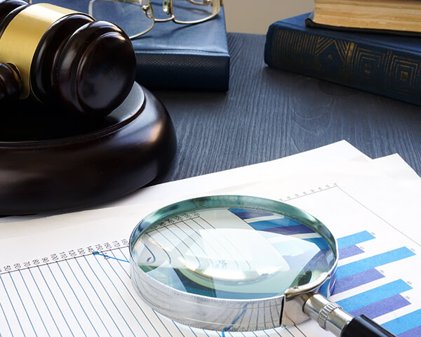 Gavel and Magnifying glass with business documents.